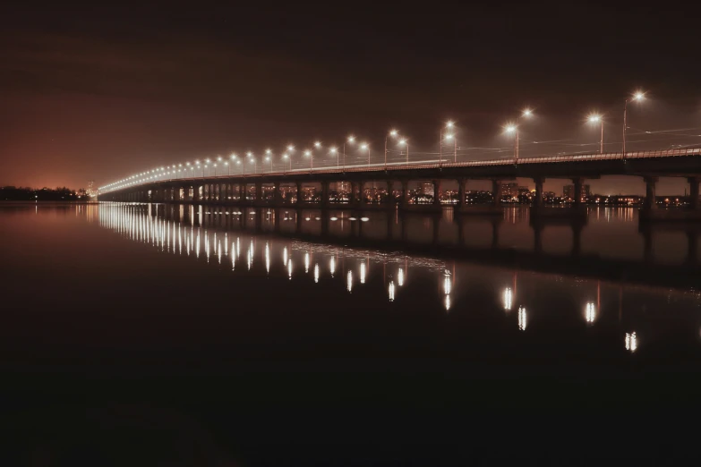 a long bridge spanning over water with lights on it