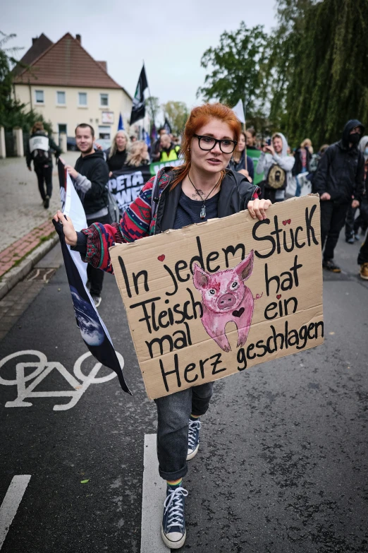 a woman is walking down the street holding a sign