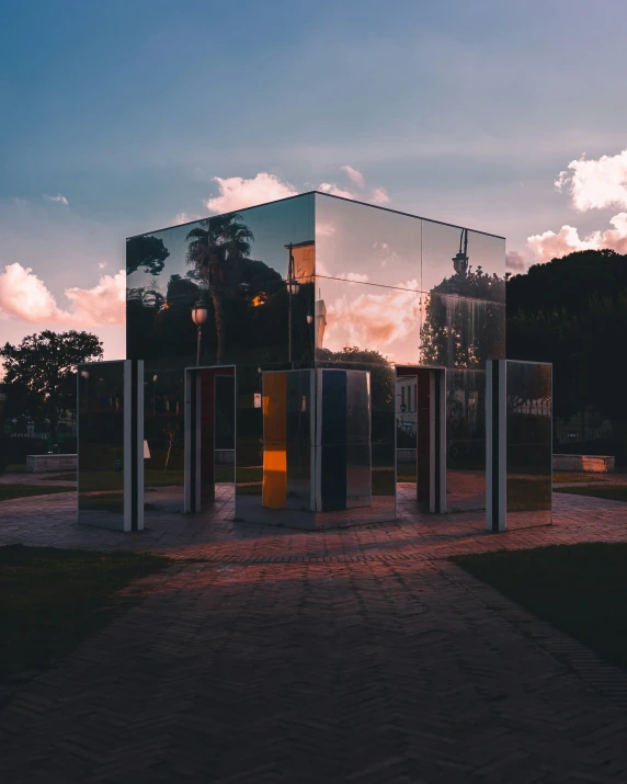 several mirrored objects standing in front of a cloudy sky