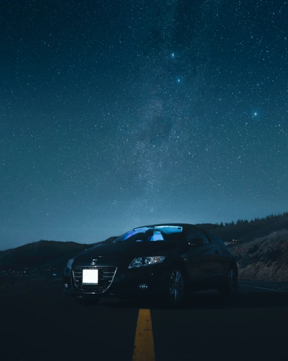 cars are parked on the side of a road under a night sky