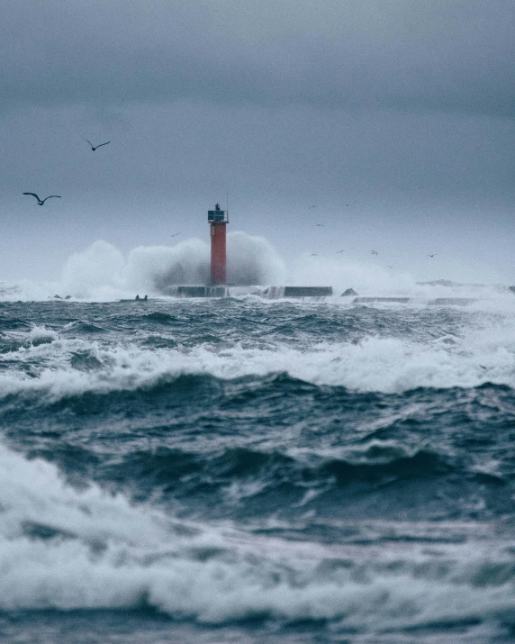 there is a red lighthouse sitting in the ocean