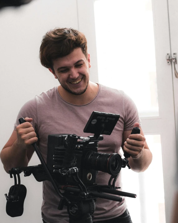 a young man standing next to a camera with a smile on his face