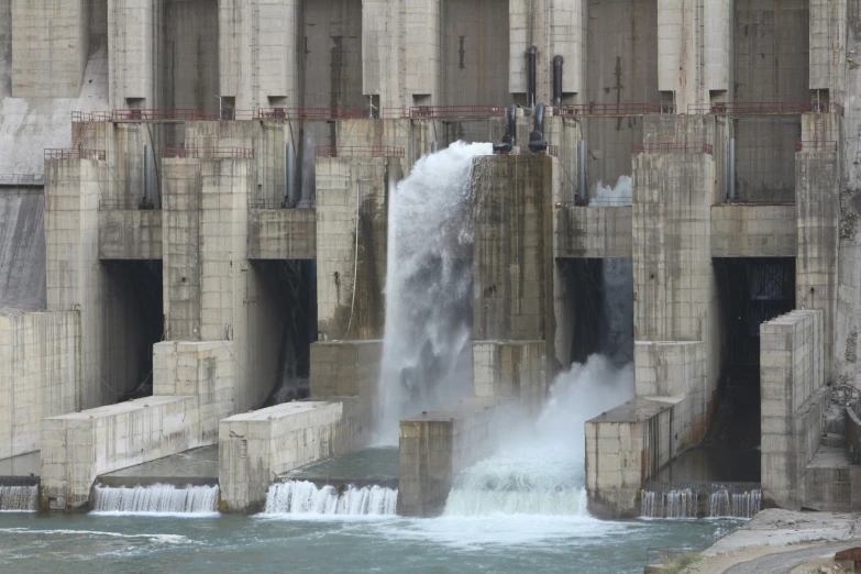 a waterfall is pouring water out of the side of a bridge