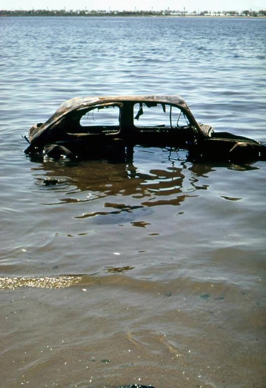 a wrecked car sitting in the water in the middle of a lake