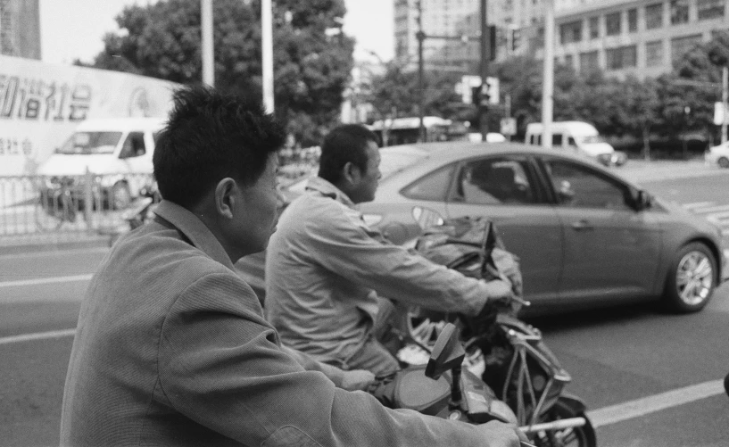 an older couple riding a scooter down the street