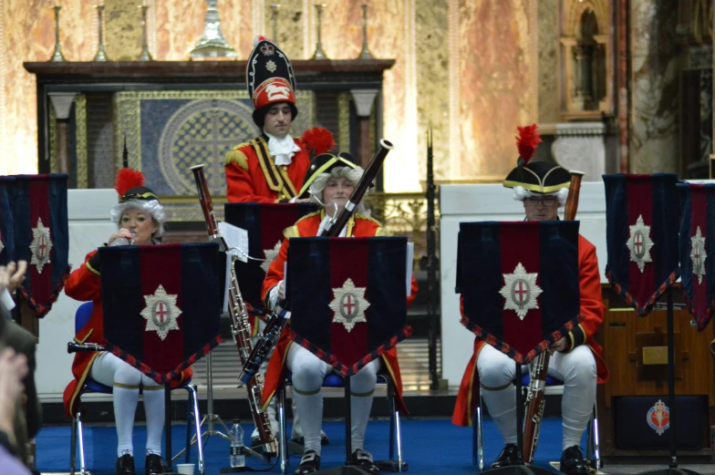 some uniformed men with red uniforms stand next to a conductor