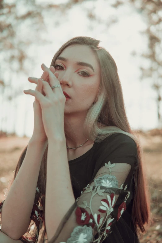 a woman sitting in the woods, smoking a cigarette