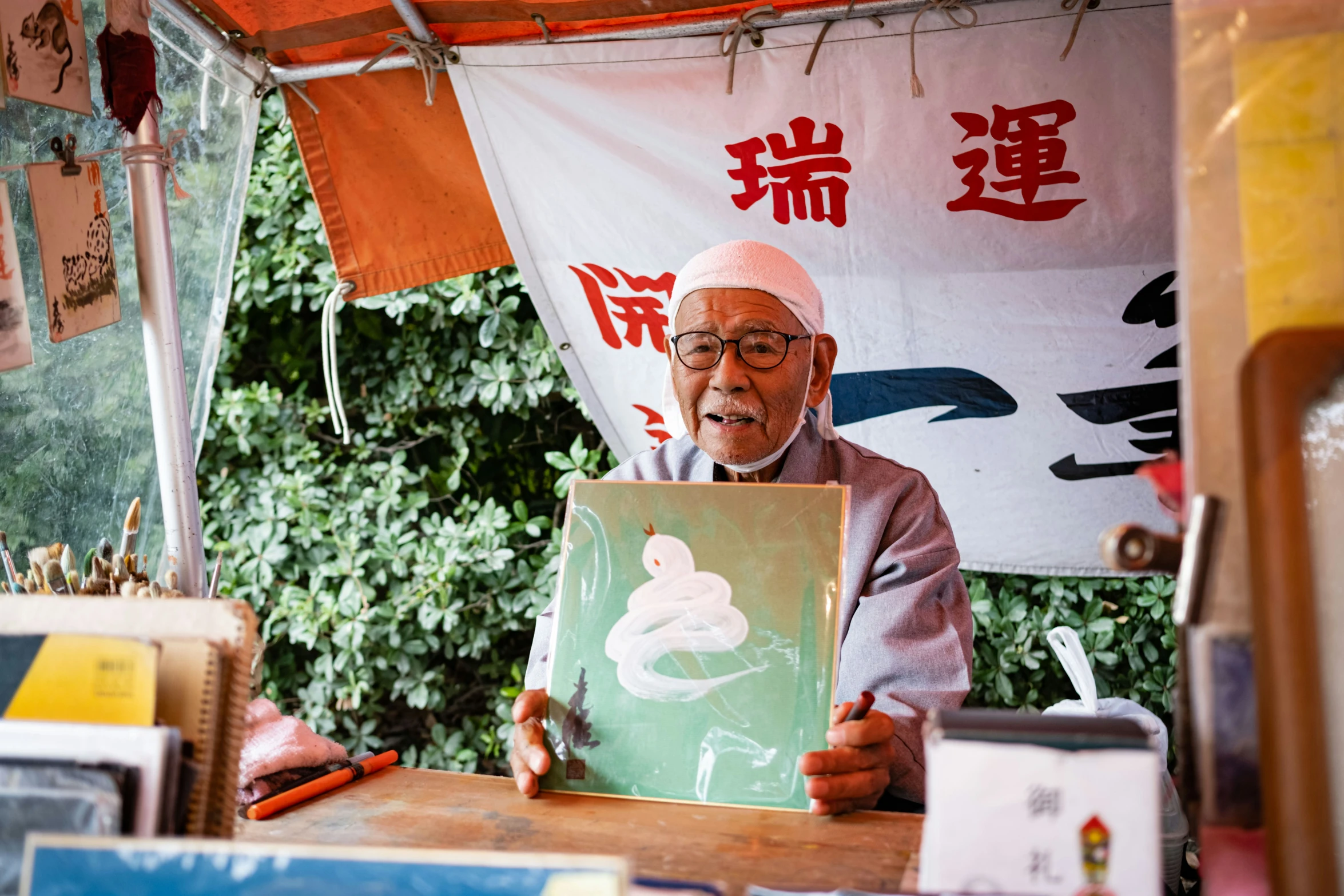 an elderly man holding a painting with asian writing