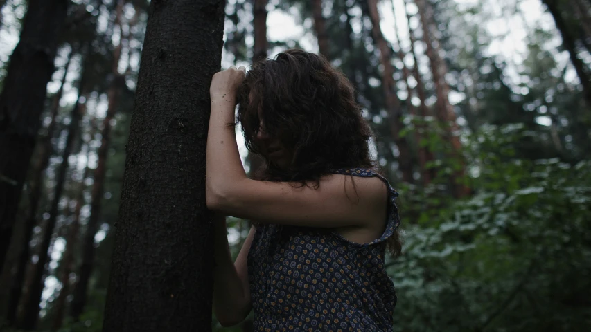 woman standing next to a tree in the woods