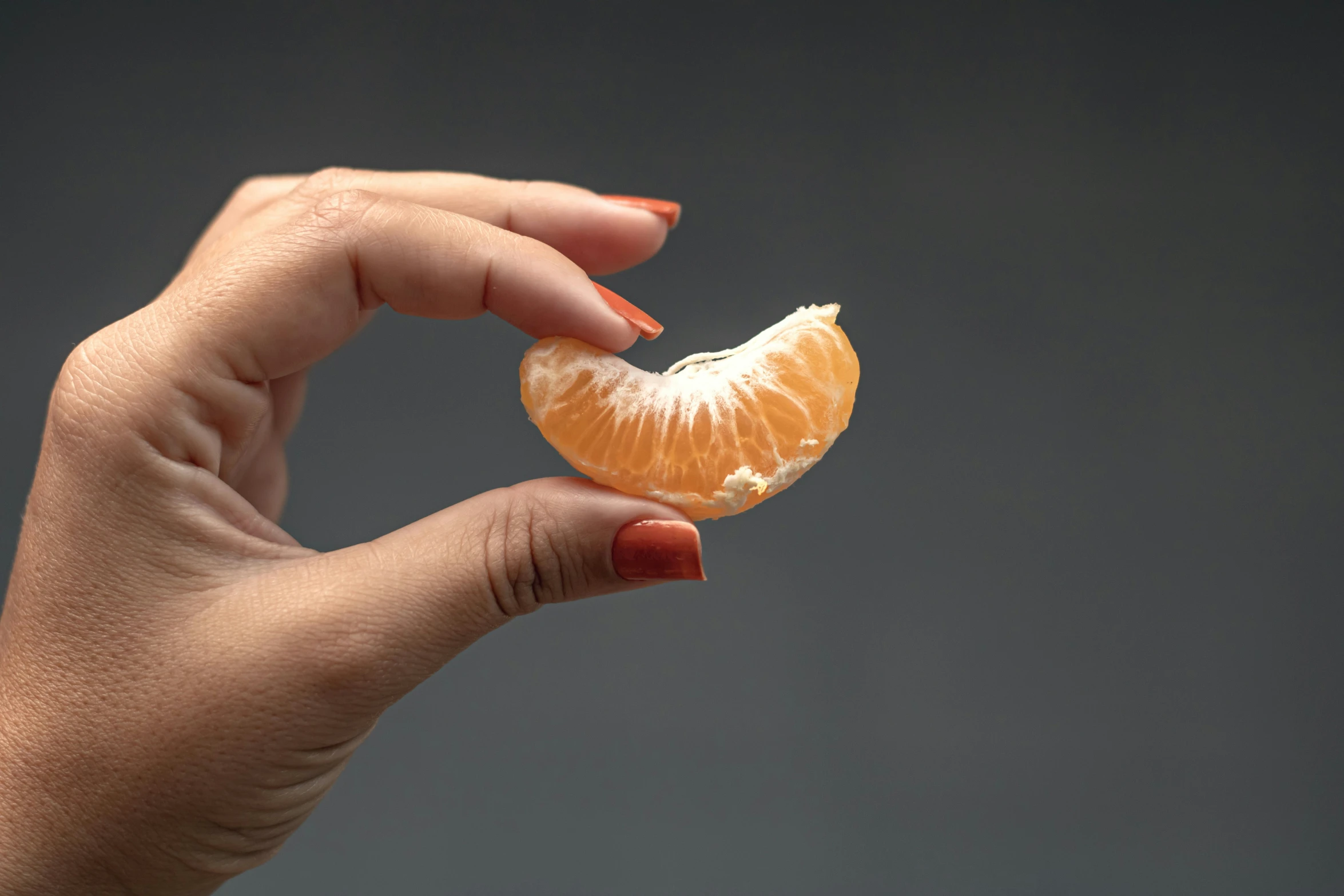 a woman holding an orange half up to her mouth