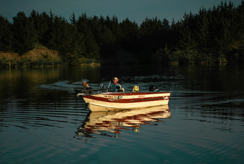 a boat with a man sitting in the bow of it, on water