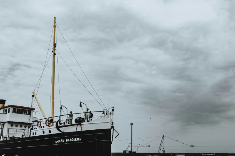 the black and white sail boat is near the dock