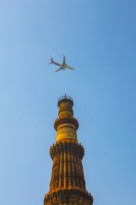 an airplane flying over a tower under a blue sky