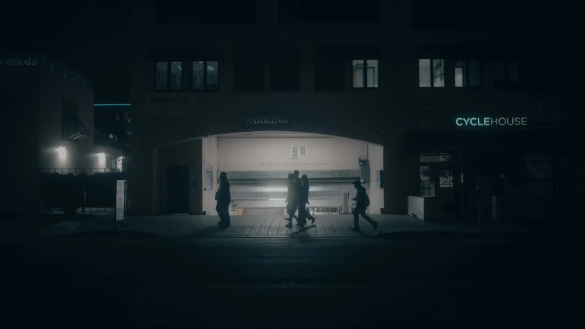 three people walk out of a dimly lit building at night