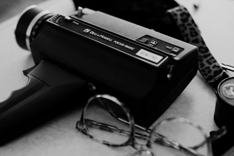 a hair dryer sitting on top of a counter next to a pair of glasses