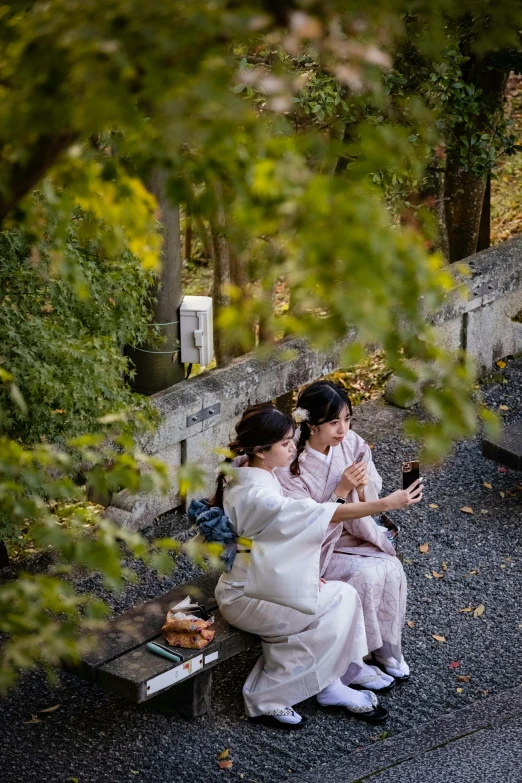 two women sitting on a bench and looking at a cellphone