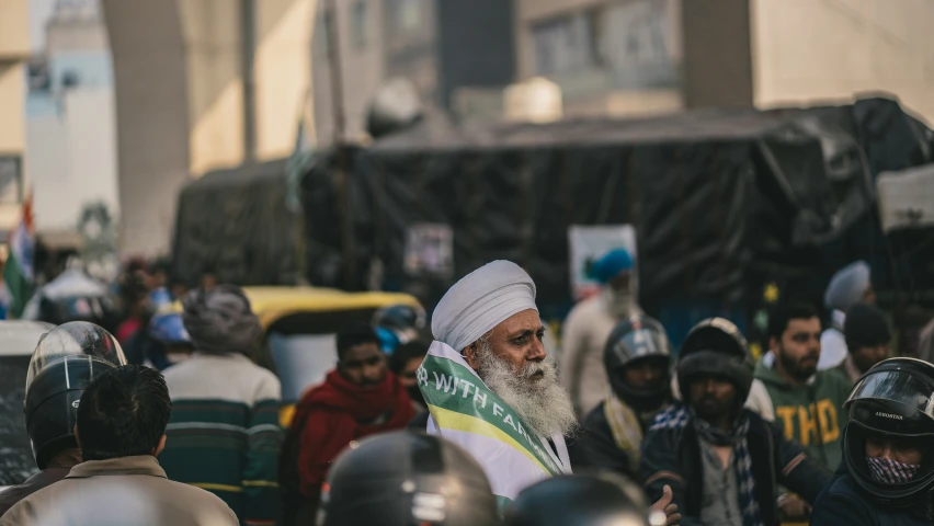 a man with a white turban is surrounded by people