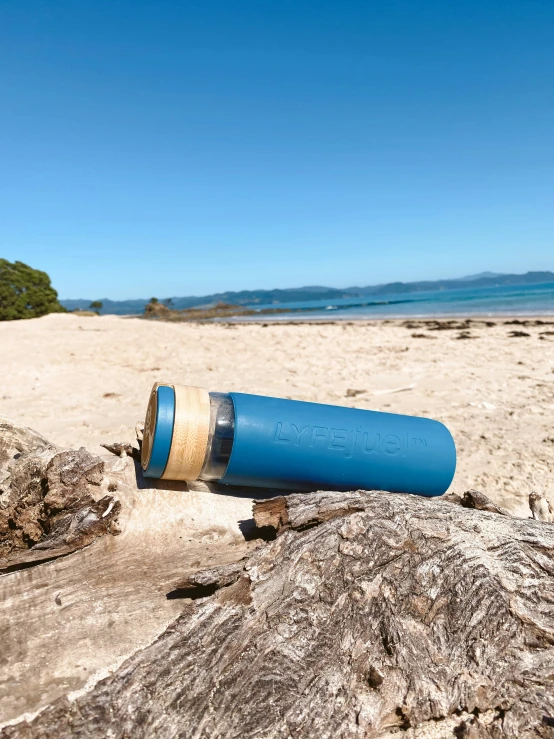 blue trash can placed on the beach with an ocean view