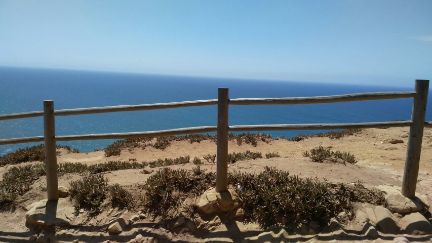 a wooden fence stands near the ocean