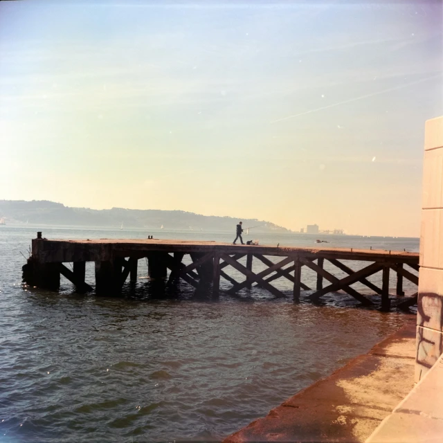 a man walks on a pier over the water