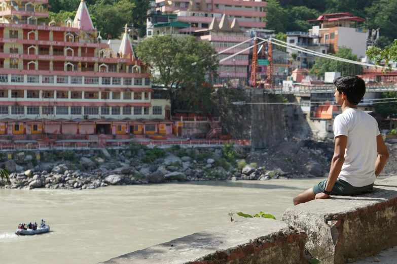 a man sitting on a ledge looking out at a body of water