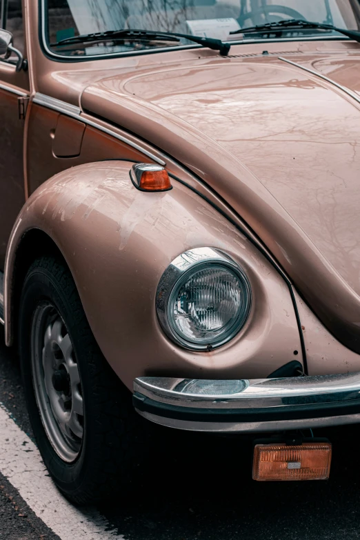 a tan volkswagen beetle is parked in a lot