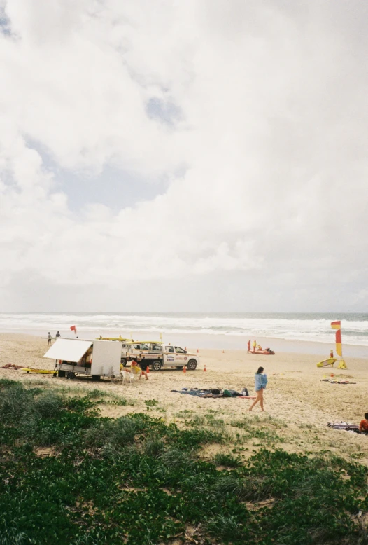 two people walk on the beach, near a tent