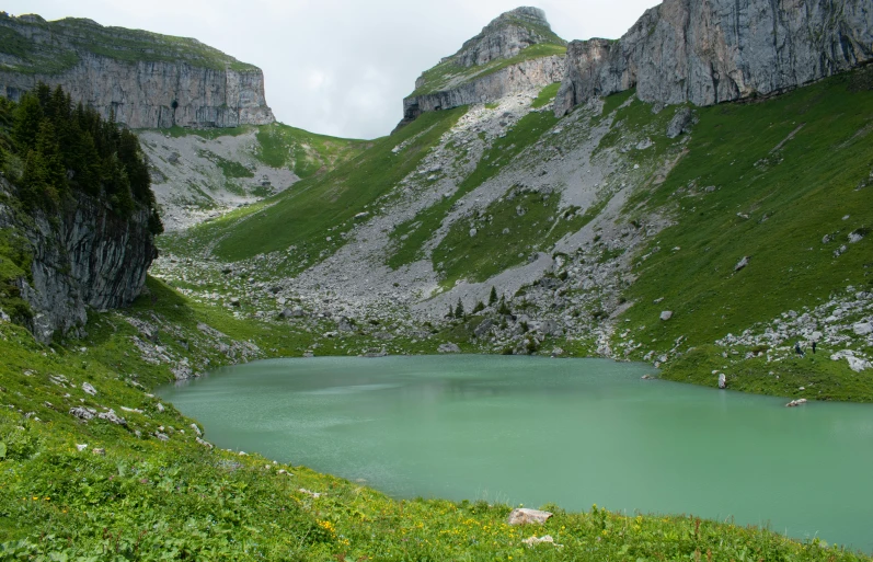 a body of water next to a green mountain