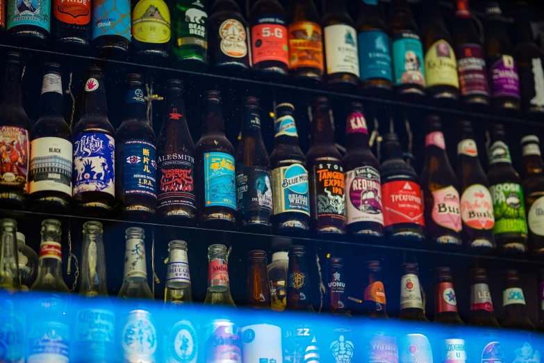 a wall full of beer bottles with many different varieties of bottle colors