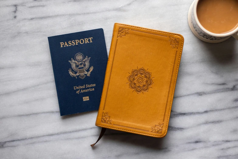 two different passports sitting on top of a marble table next to a cup of coffee