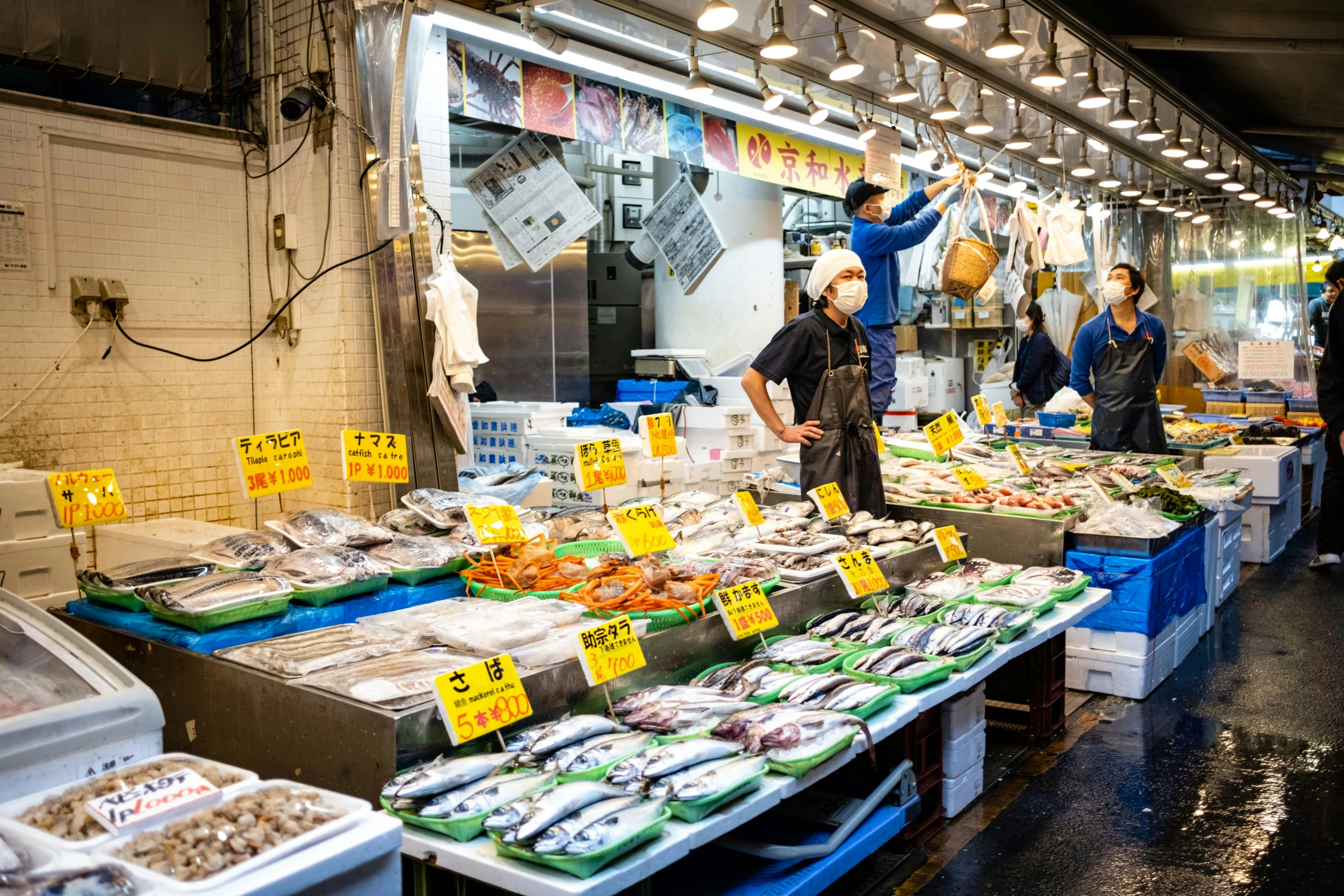 people buying seafood at an open market on a rainy night