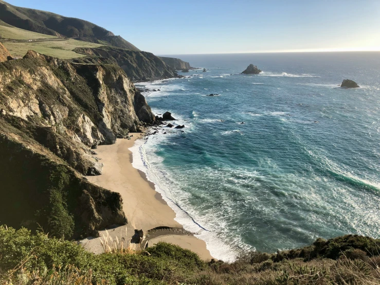 the view of a beach and some hills and water