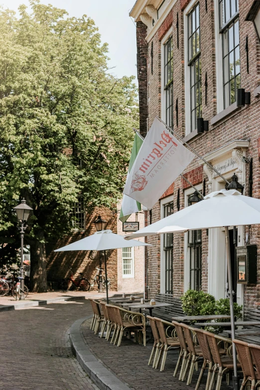 many tables with white umbrellas sit on the street