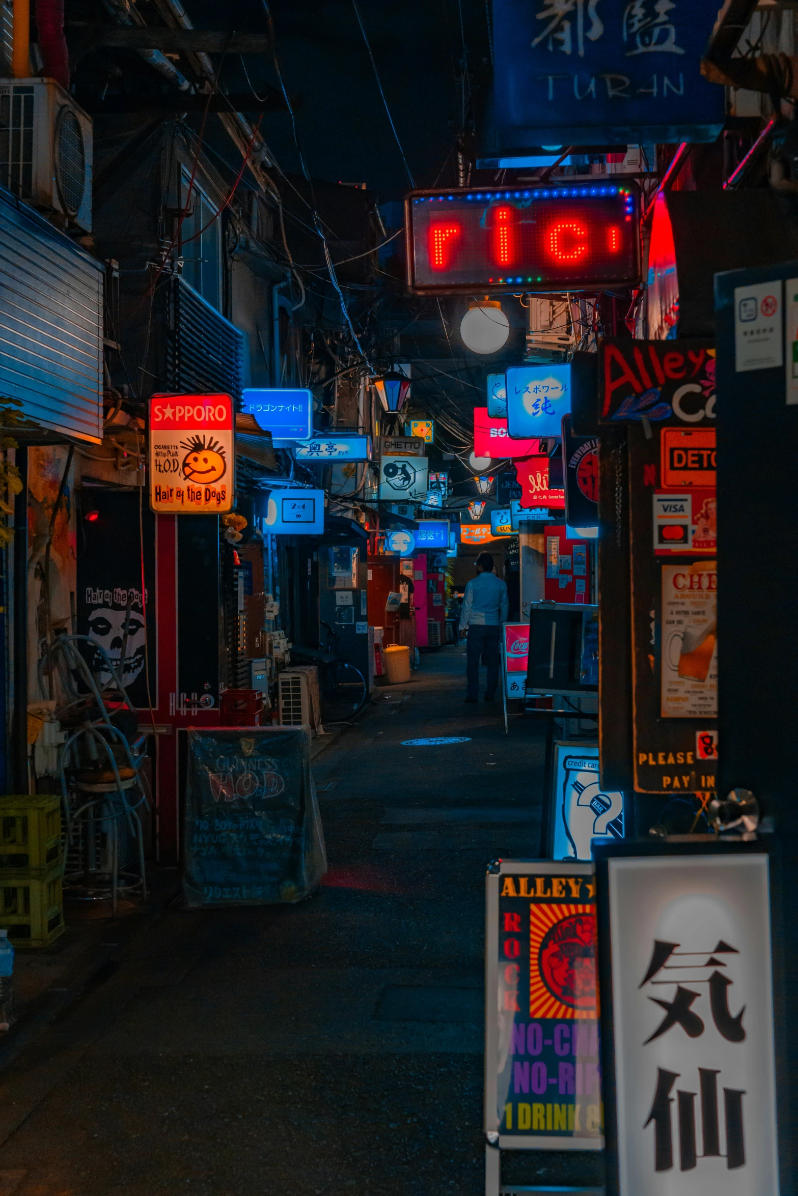 a very narrow alley way with bright signs and neon lights