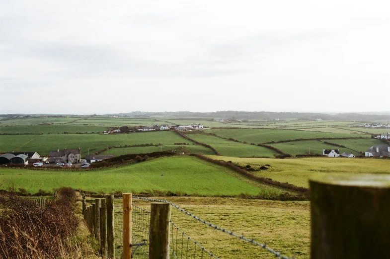farm land and country houses in the distance with a fence surrounding them