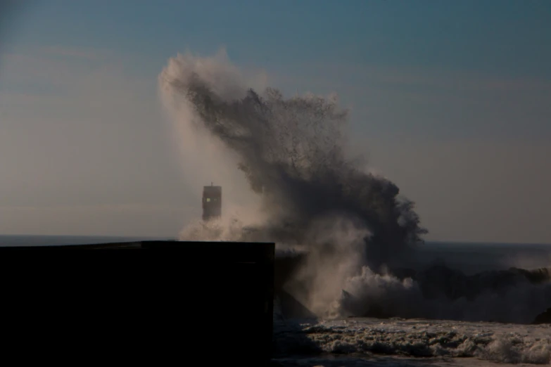 a big wave breaks over a ship that has just reached shore