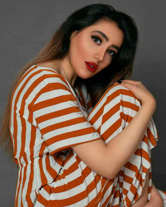 a woman with long hair, dressed in an orange and white striped shirt