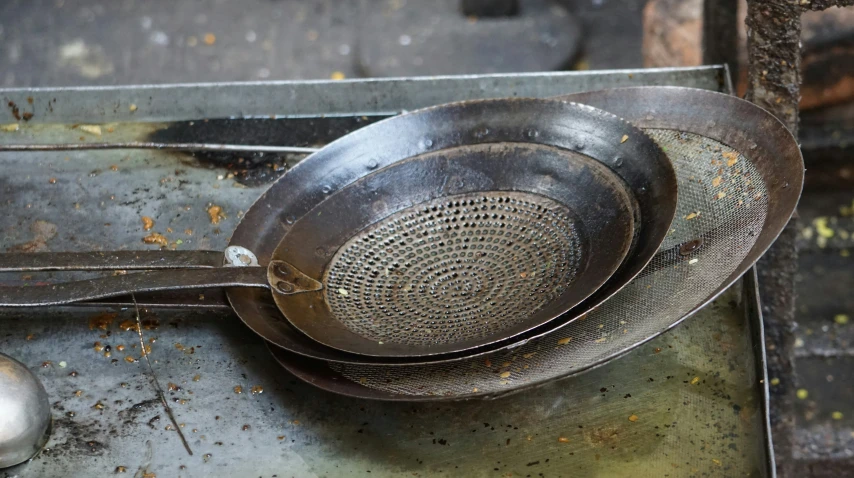 several strainers on top of a metal surface