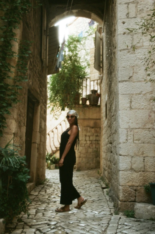 a woman with headdress standing under a stone archway