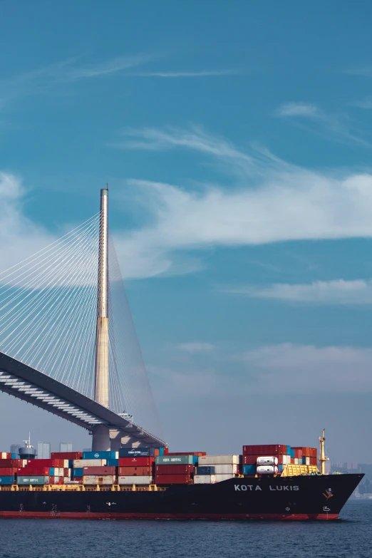 a large cargo ship under a very tall bridge