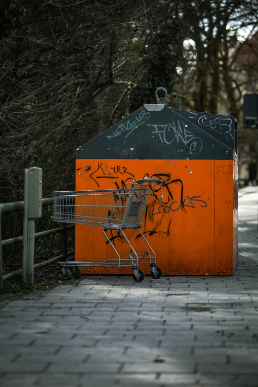 a shopping cart on brick road next to fence and green trees