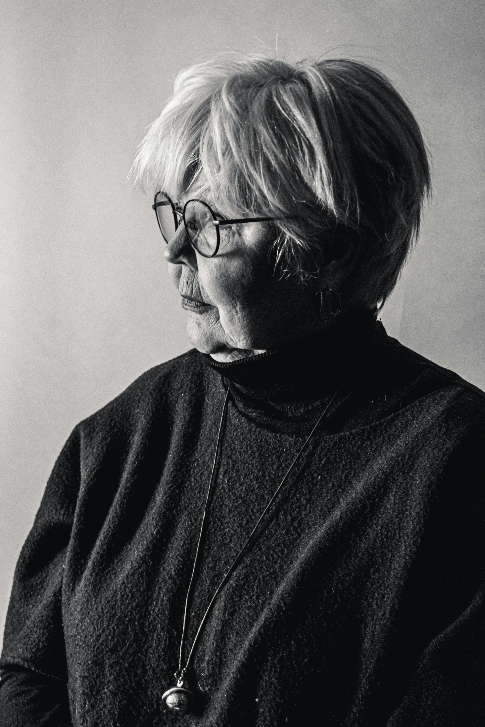 an older woman wearing glasses standing next to a wall