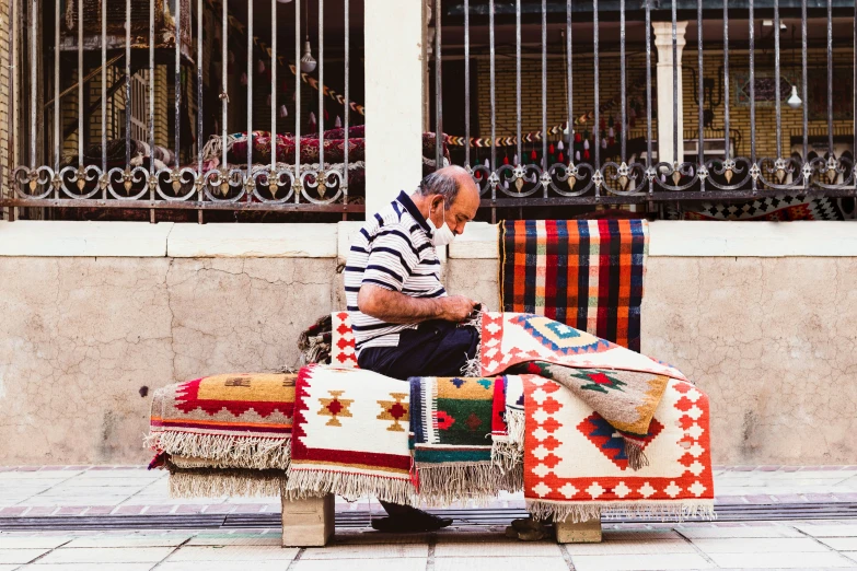 an old man sitting on top of a colorful couch