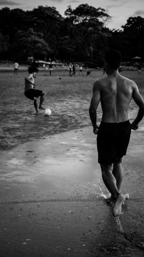 a group of s playing soccer on a beach