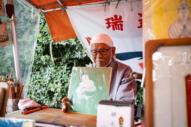 a man holding up a piece of art on a table