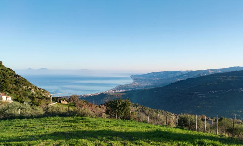 a small grassy hill with a body of water in the distance