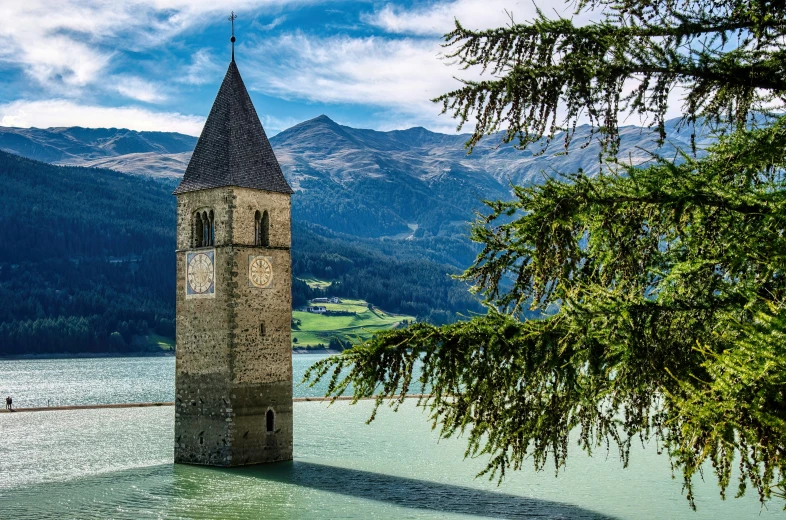 a tower stands by the water in the mountains