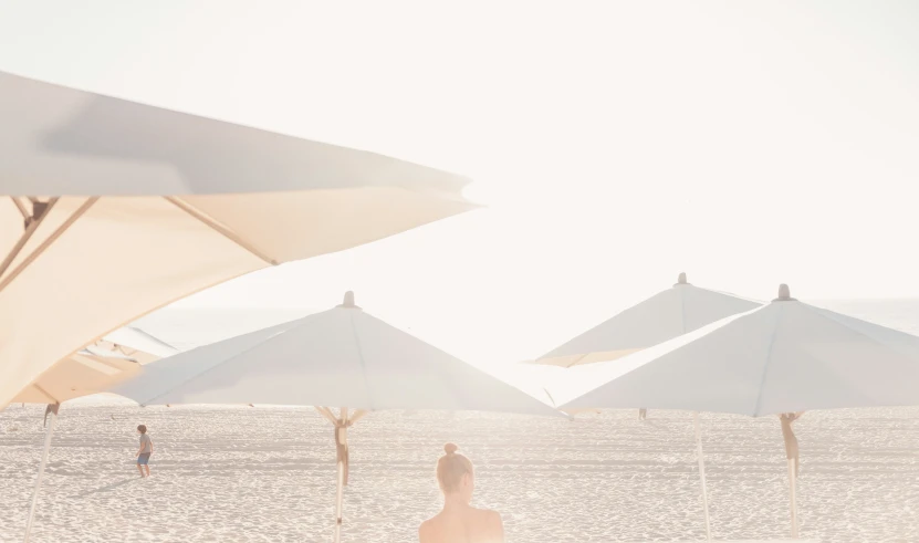 a couple of people that are standing under umbrellas on a beach