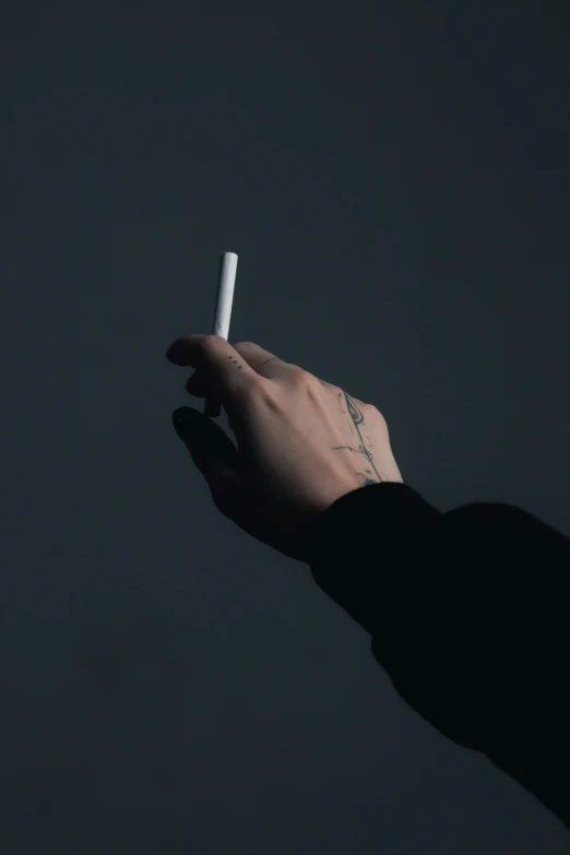 a person with tattoos holding a cigarette up