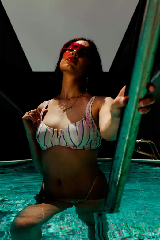 a woman sitting in a pool holding up the handle of a water slide